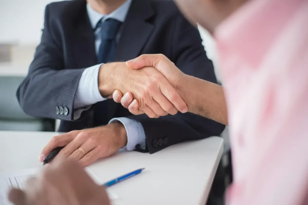 Dua orang profesional berjabat tangan setelah mencapai kesepakatan negosiasi bisnis